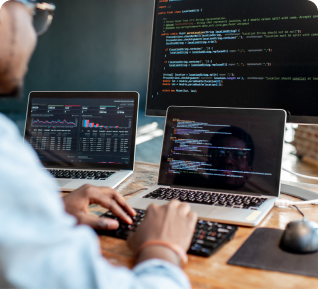 man with glasses developing app with 3 monitor 