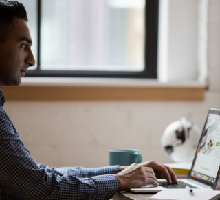 a side view man smiling in front of laptop